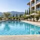 Clean hotel swimming pool with organized deck chairs and landscaping